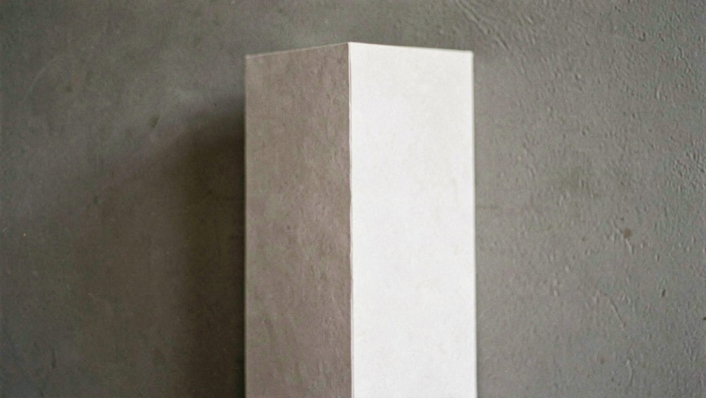 Un plan de salle imprimé posé sur une table de service, rectangles de tables tracés au crayon et noms reportés à la main, lumière blanche, vue de dessus.