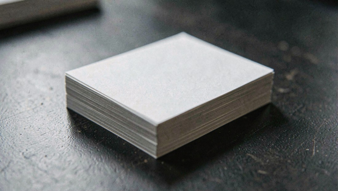 Bureau en fin de journée, un dossier papier ouvert près d’un ordinateur portable affichant un registre d’entreprises, lumière de lampe latérale, cadrage serré sur les mains et les documents.